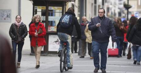 Una joven transita en bicicleta por la céntrica calle Gondomar, entre numerosos peatones.